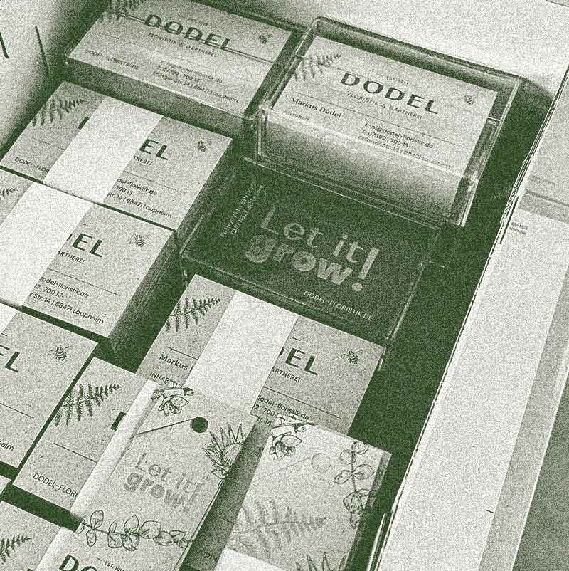 Etiketten und Visitenkarten mit DODEL-Logo und ‘Let it grow!’-Design aus Naturpapier, in Karton. Foto ohne Farbe.